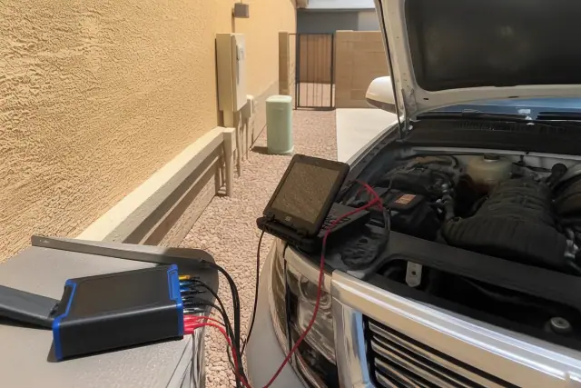 Diagnostic equipment connected to an open car engine in a utility area in Phoenix, AZ.
