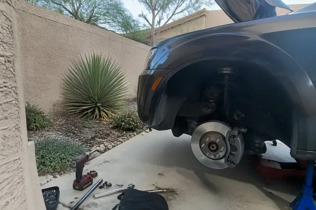 Technician performing a mobile brake repair on a vehicle at a residential home in Phoenix, AZ.