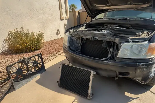 Vehicle with its hood raised for radiator repair on a concrete pad at a home in Phoenix, AZ.