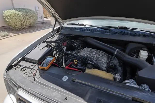 Car with hood raised during a pre-purchase inspection on a concrete driveway in Phoenix, AZ.