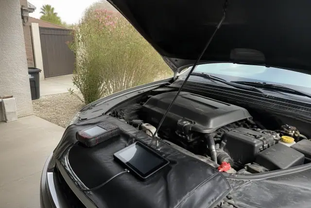 Pre-purchase car inspection with the hood open and diagnostic tools on a residential driveway in Peoria, AZ.