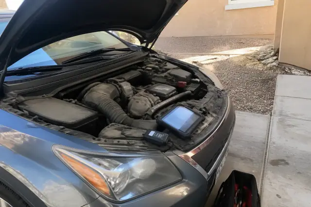 Mobile mechanic performing a pre-purchase car inspection on a vehicle in a residential driveway in Tempe, AZ.