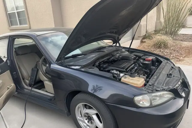 Technician performing a pre-purchase car inspection on a vehicle with the hood open at a home in Avondale, AZ.