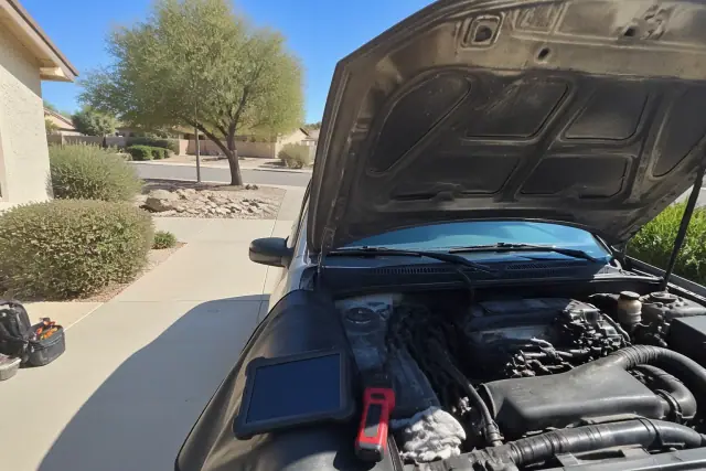 Mechanic performing a pre-purchase car inspection on a vehicle in a residential driveway in Goodyear, AZ.