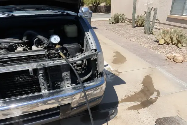 Technician performing a radiator pressure test on a car at a residential driveway in Phoenix, AZ.