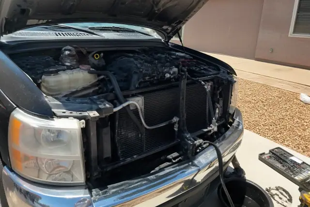 Mobile mechanic performing a radiator and cooling system repair on a car in a driveway in Goodyear, AZ.