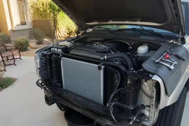 A technician performs a radiator and cooling system repair on a car in a residential driveway in Surprise, AZ.