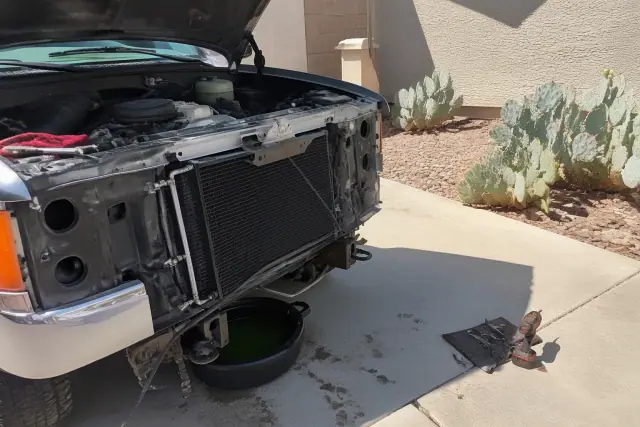 A mobile mechanic performs a radiator and cooling system repair on a car in a driveway in Gilbert, AZ.