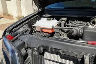 Clean coolant reservoir and new radiator hose connections under a car hood in a Phoenix, AZ driveway.