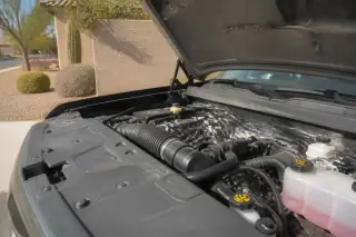 Finished cooling system installation with new reservoir caps under an open car hood in Phoenix, AZ.