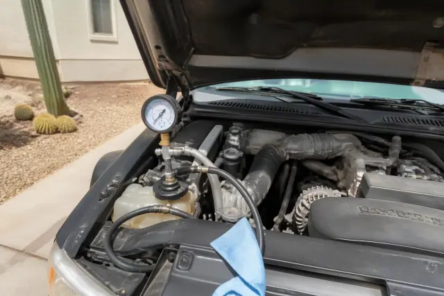Technician performing a radiator cooling system leak test on a vehicle engine in Phoenix, AZ.