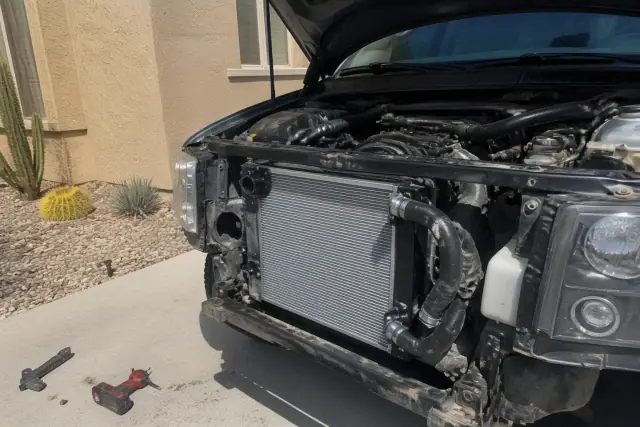 Radiator replacement in progress on a vehicle engine in a residential yard in Phoenix, AZ.