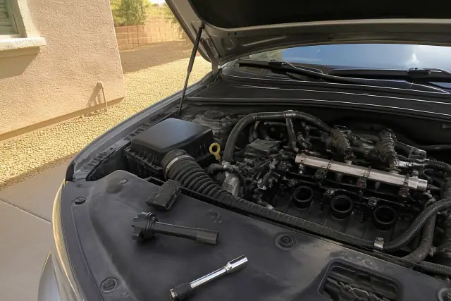 Engine bay with spark plug socket and ignition coil replacement on a vehicle in Phoenix, AZ.