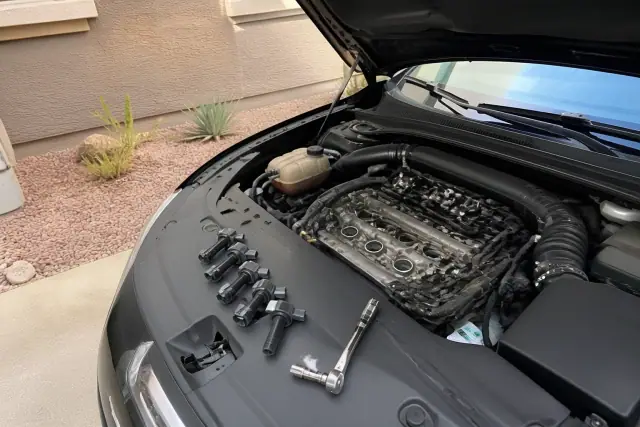 Technician replacing spark plugs and ignition coils in a vehicle engine bay at a residence in Avondale, AZ.
