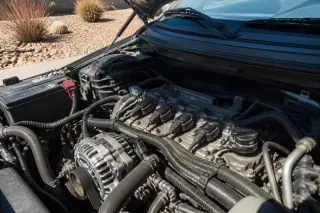New ignition coils and wiring harness installed in a car engine bay under bright sunlight in Phoenix, AZ.