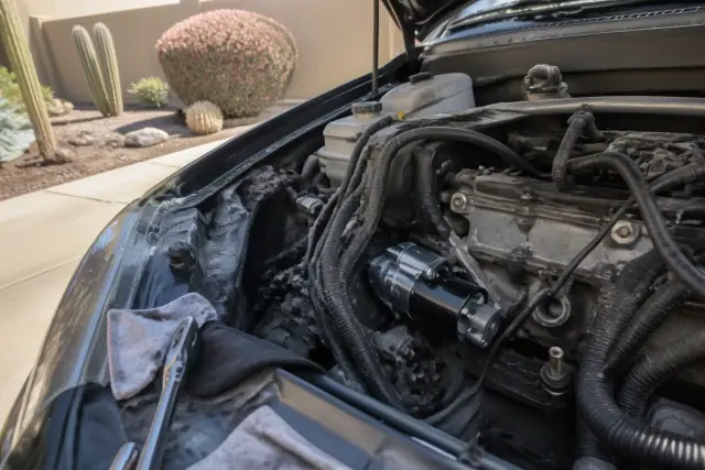 Engine bay of a vehicle with a new starter being installed in a driveway in Goodyear, AZ.