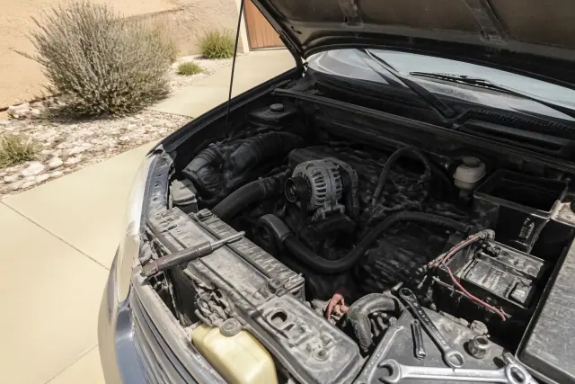 New alternator being installed in a vehicle engine bay at a residential driveway in Phoenix, AZ.
