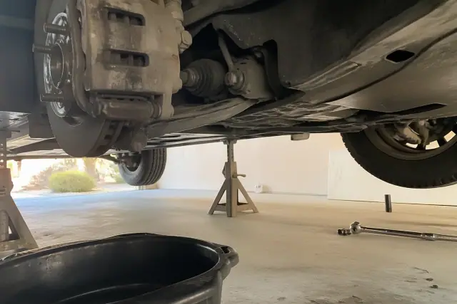 Vehicle undercarriage and brake caliper inspection on jack stands in a Phoenix, AZ garage.