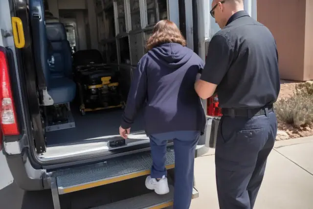 An escort assists a patient through a doorway into a medical transport vehicle in Phoenix, AZ.