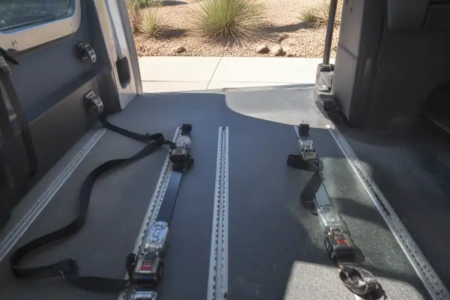 Wheelchair securement station with tie-down straps in a medical transport van parked in Phoenix, AZ.