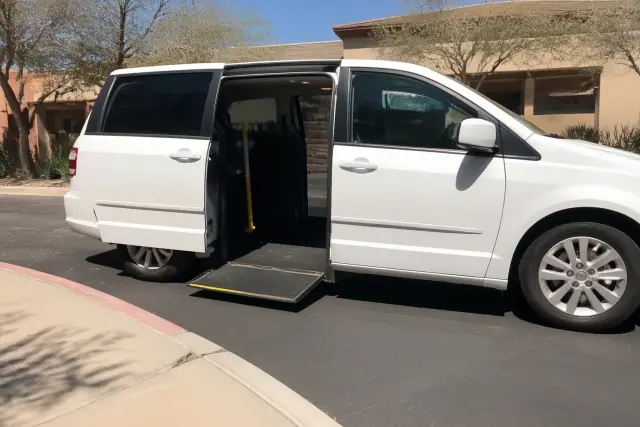 Ambulatory medical transport vehicle with open sliding doors parked on the curb in Mesa, AZ.