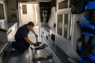 Technician cleaning safety restraints in a medical transport van cabin in Phoenix, AZ.