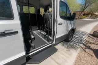 Open side door of a transport van with grab rails and non-slip flooring parked in Phoenix, AZ.
