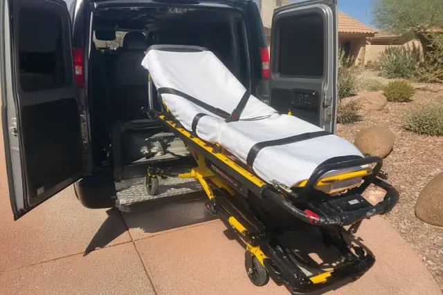 A secured stretcher with safety belts being loaded into a transport van at a residence in Phoenix, AZ.