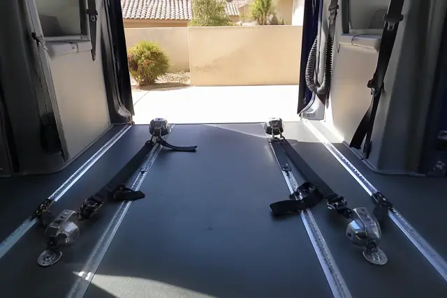 Heavy-duty four-point wheelchair tie-down straps locked into the floor tracks of a transport van in Phoenix, AZ.