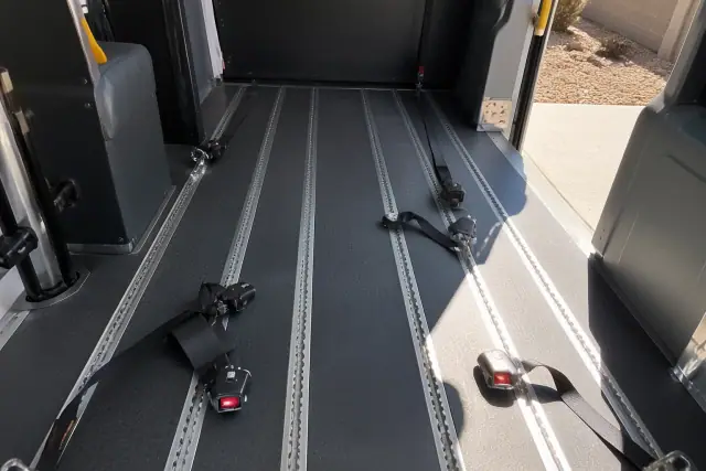 Interior of a bariatric transport vehicle showing wheelchair tracking and tie-down straps in Phoenix, AZ.