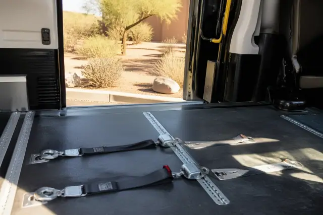 Wheelchair securement straps on a van floor with desert landscape visible through the door in Phoenix, AZ.