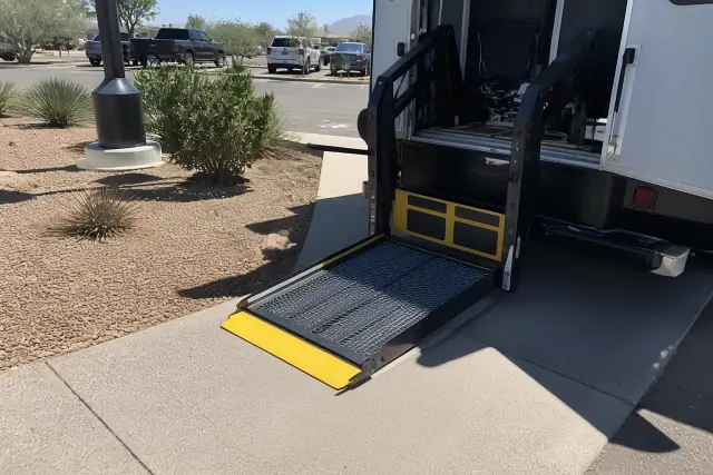 Automated hydraulic lift ramp lowered to the ground for bariatric medical transport at a job site in Glendale, AZ.