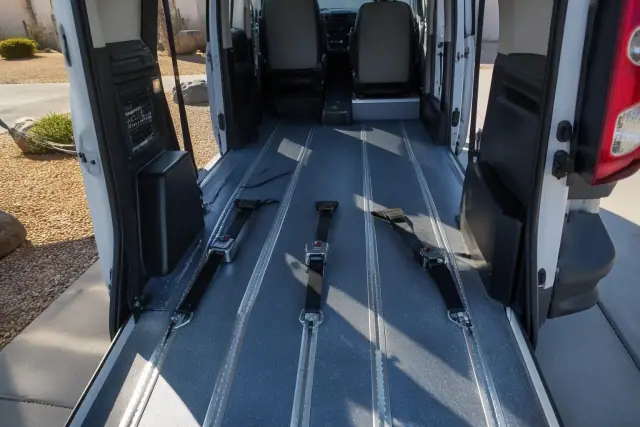 Wheelchair securement station with heavy-duty tie-down straps and floor tracking in a transport vehicle in Sun City, AZ.