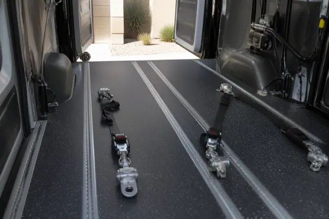 Wheelchair securement station with floor tracking and heavy-duty tie-down straps in a medical transport van in Surprise, AZ.