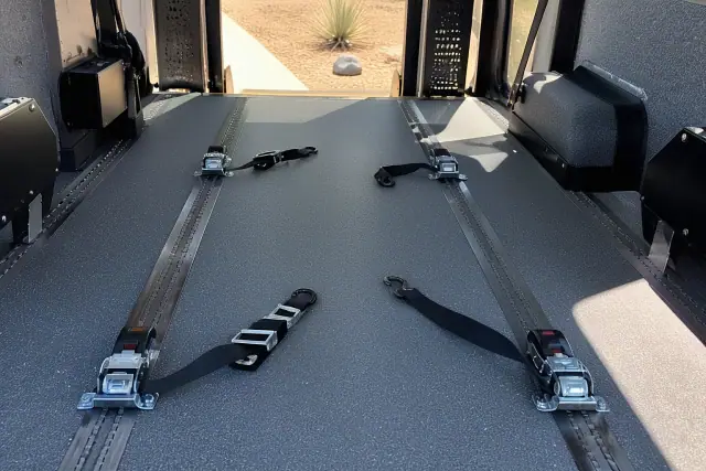 Wheelchair floor tracking and heavy-duty tie-down straps inside a medical transport van in Phoenix, AZ.