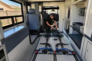 Technician tidying safety straps inside a bariatric transport vehicle in Phoenix, AZ.