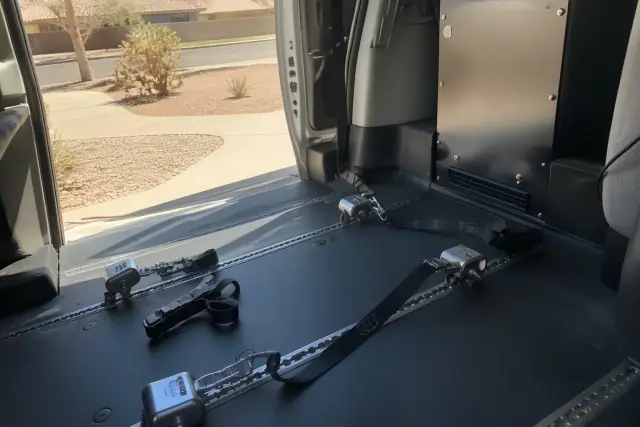 Wheelchair tie-down straps secured to floor tracks inside a vehicle in Phoenix, AZ.