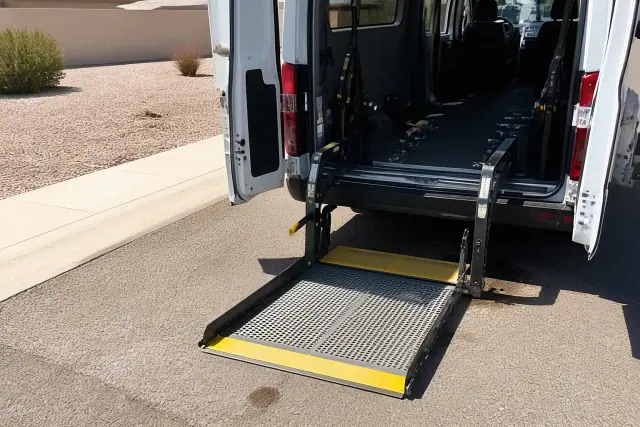 Hydraulic lift ramp deployed on a wheelchair transport vehicle in Phoenix, AZ, with tie-down straps visible on the floor.