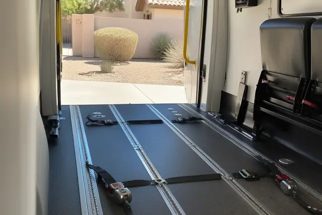 Wheelchair securement station with four-point tie-down straps inside a medical transport van in Mesa, AZ.