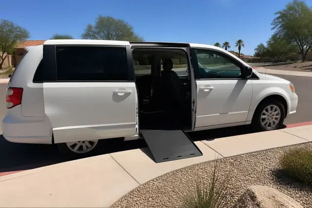 Medical transport vehicle with open side doors parked at a curb in Sun City, AZ, surrounded by desert landscaping.