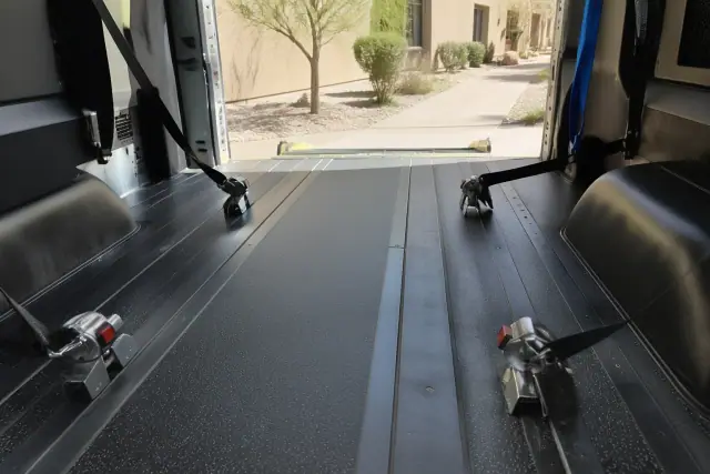 Interior of a medical transport van with wheelchair tie-down straps and floor tracks in Surprise, AZ.