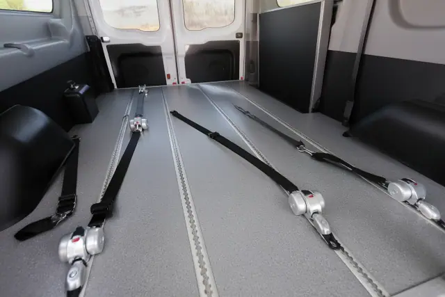 Interior floor of a medical transport vehicle with secure wheelchair tie-down straps in Peoria, AZ.