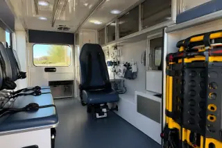 Organized interior cabin of a medical transport vehicle with storage cabinets and safety straps in Phoenix, AZ.