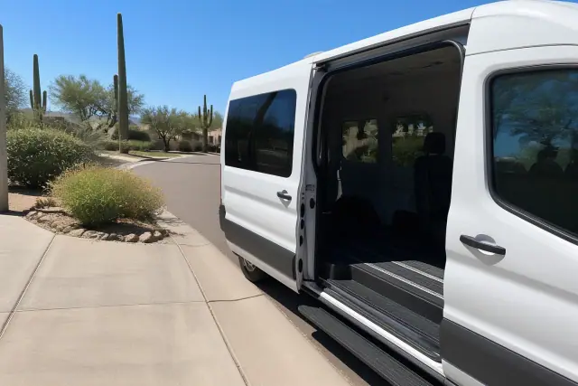 Medical transport van parked curbside with open sliding doors in Scottsdale, AZ, surrounded by desert cacti and flora.