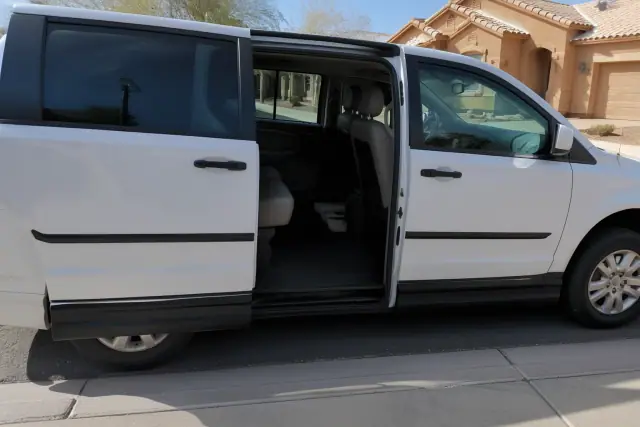 Medical transport van parked at a curb in Surprise, AZ, with side sliding doors open for passenger boarding.