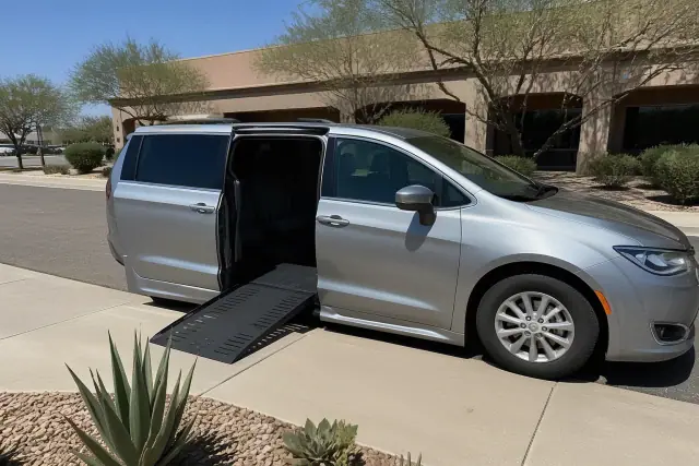 Medical transport van with a deployed wheelchair ramp parked on a concrete surface in Tempe, AZ.