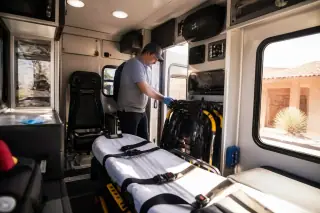 Service professional checking medical equipment and safety restraints inside a transport van in Phoenix, AZ.