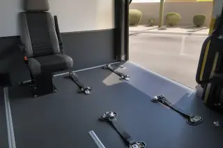 Four-point tie-down straps and floor tracking installed in a transport van door, seen from a desert street in Phoenix, AZ.