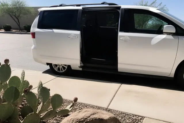 Medical transport van with side doors open for boarding on a sidewalk with desert landscaping in Phoenix, AZ.