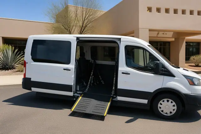 Accessible transport van with open side door and ramp at a medical facility in Phoenix, AZ.